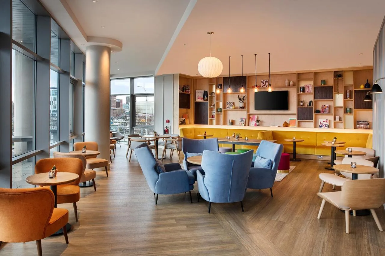 a restaurant with blue chairs and tables and windows at Leonardo Hotel Liverpool in Liverpool