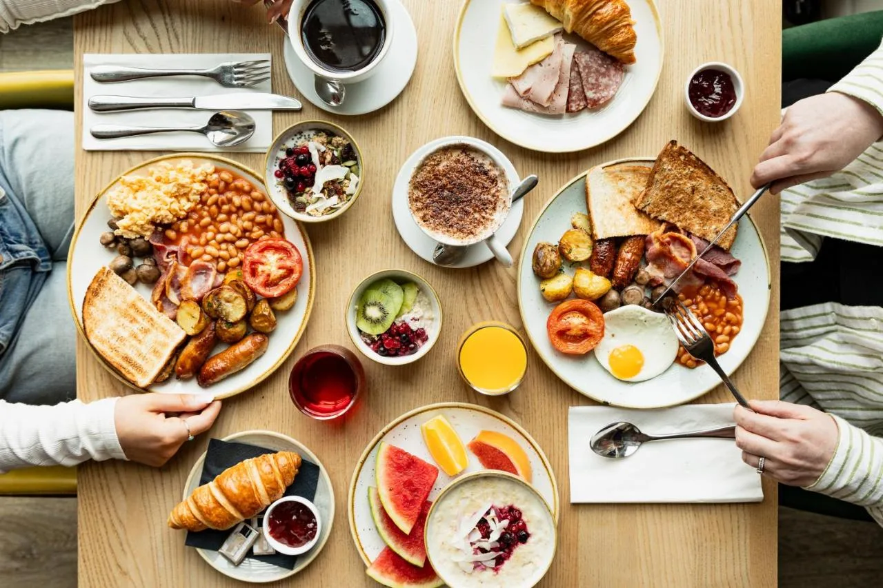 a table with plates of breakfast food on it at Leonardo Hotel Liverpool in Liverpool