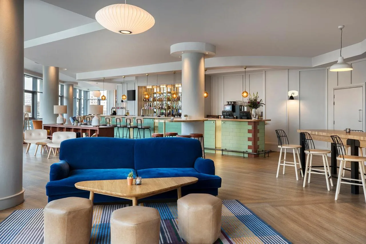 a living room with a blue couch and a table at Leonardo Hotel Liverpool in Liverpool