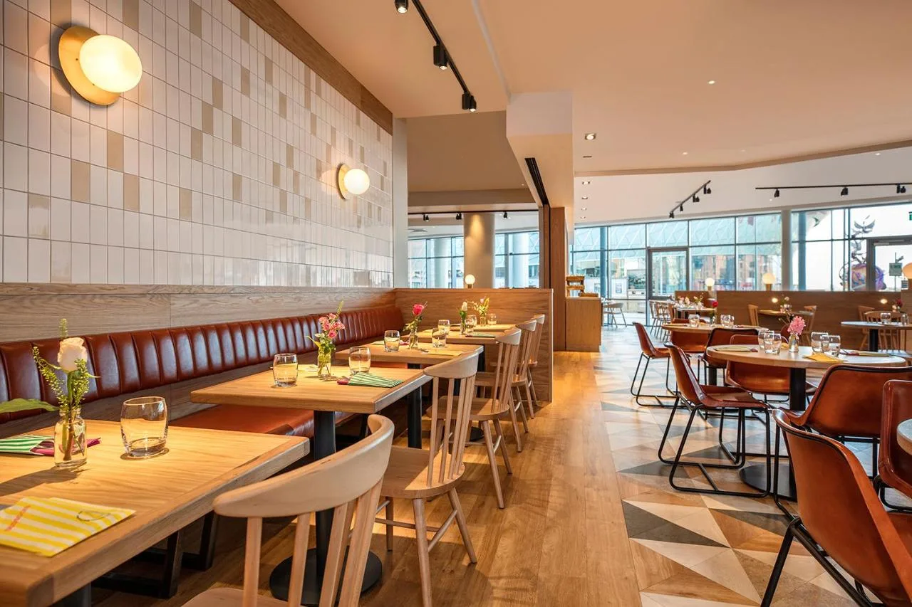 a restaurant with wooden tables and chairs and windows at Leonardo Hotel Liverpool in Liverpool