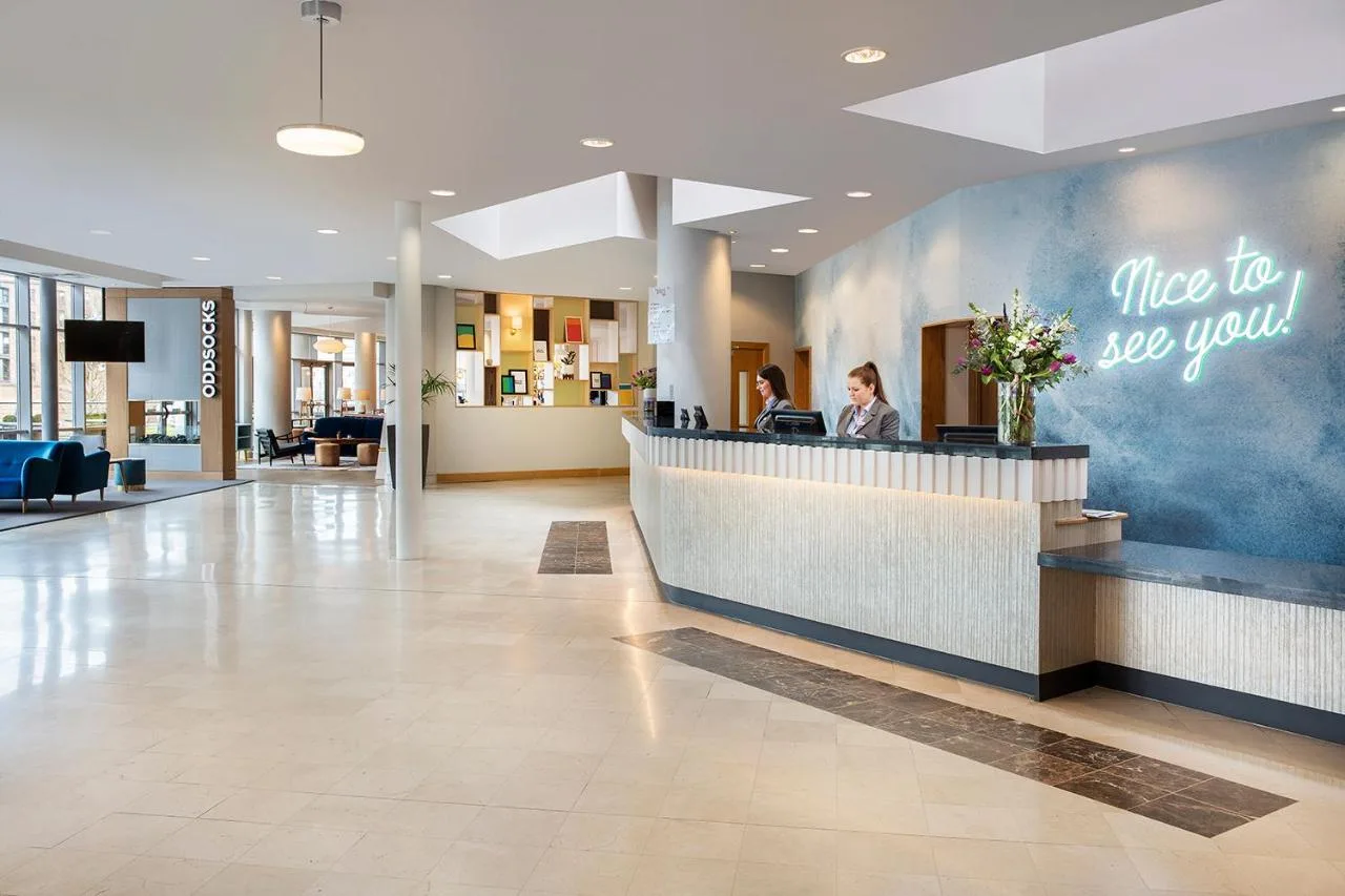 a lobby of a hospital with a woman sitting at a counter at Leonardo Hotel Liverpool in Liverpool